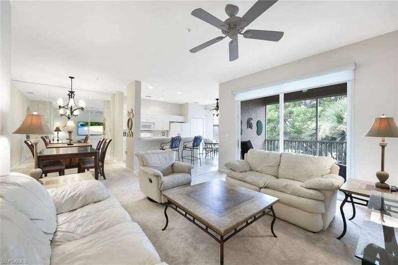 Living room featuring light colored carpet and ceiling fan with notable chandelier