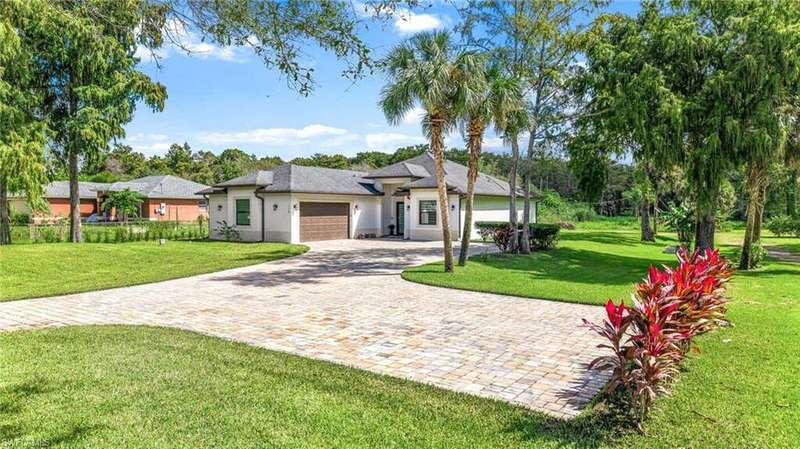 View of front of property with decorative driveway, a front lawn, a garage, and stucco siding