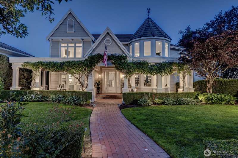 A charming brick walkway leads to the covered front porch, where cascading wisteria creates a romantic and welcoming entrance.
