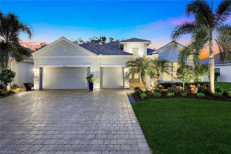 View of front of property with decorative driveway, a front yard, stucco siding, an attached garage, and stone siding