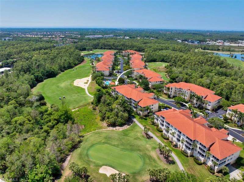 Birds eye view of property with view of golf course, a water view, and a view of trees