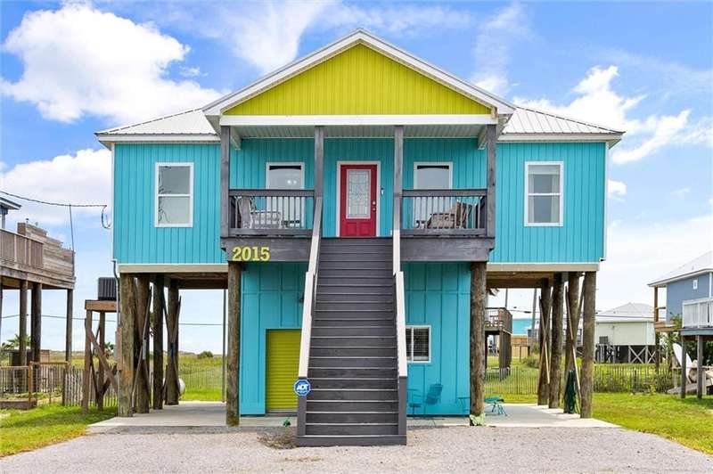 Coastal inspired home with stairs, metal roof, a carport, and a porch