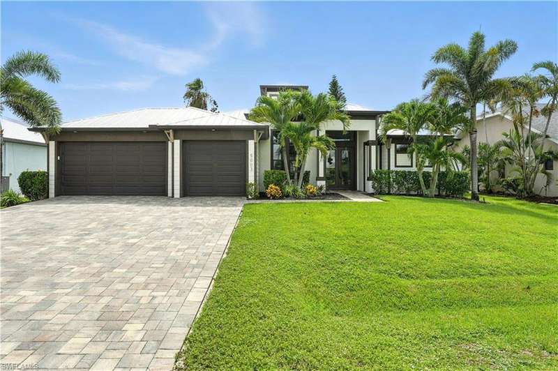 View of front of property featuring an attached garage, decorative driveway, a front lawn, and stucco siding
