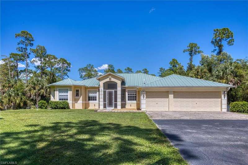 Ranch-style house with driveway, a front yard, and a metal roof