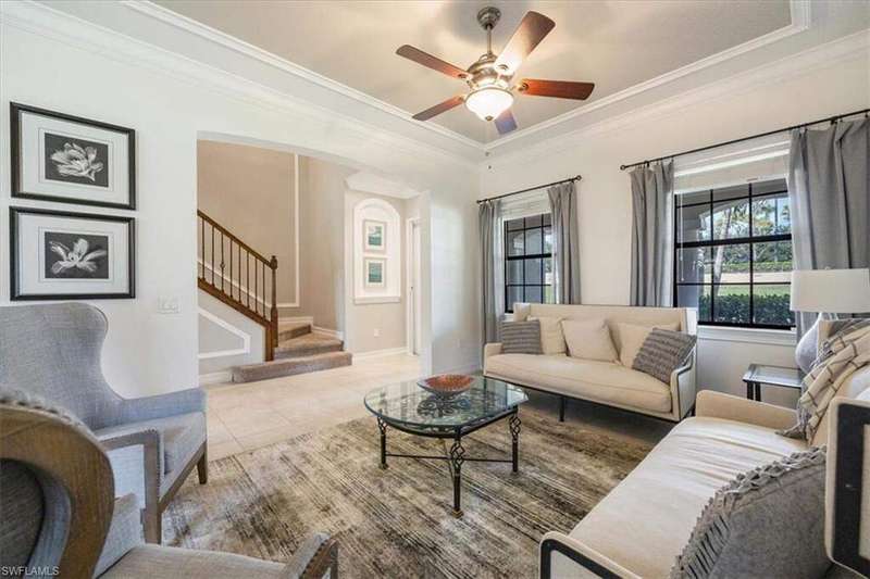 Tiled living room featuring crown molding, a ceiling fan, and stairs