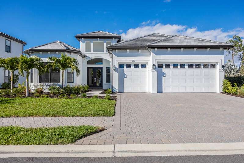 View of front facade featuring decorative driveway, an attached garage, french doors, and stucco siding