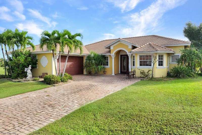 View of front of house with stucco siding, a front yard, a tile roof, and decorative driveway