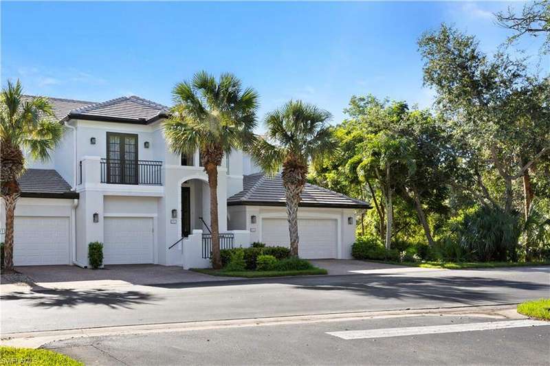 View of front facade with a balcony, driveway, a tile roof, stucco siding, and french doors
