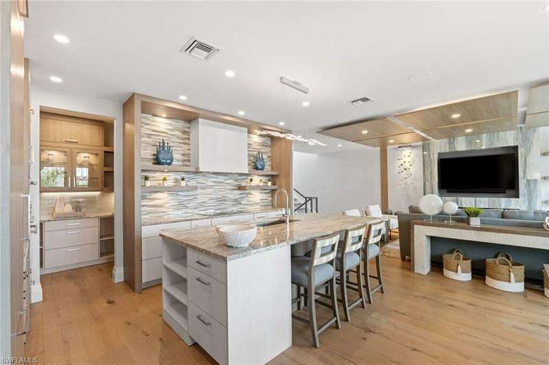 Kitchen featuring light stone counters, sink, white cabinetry, and a kitchen island with sink