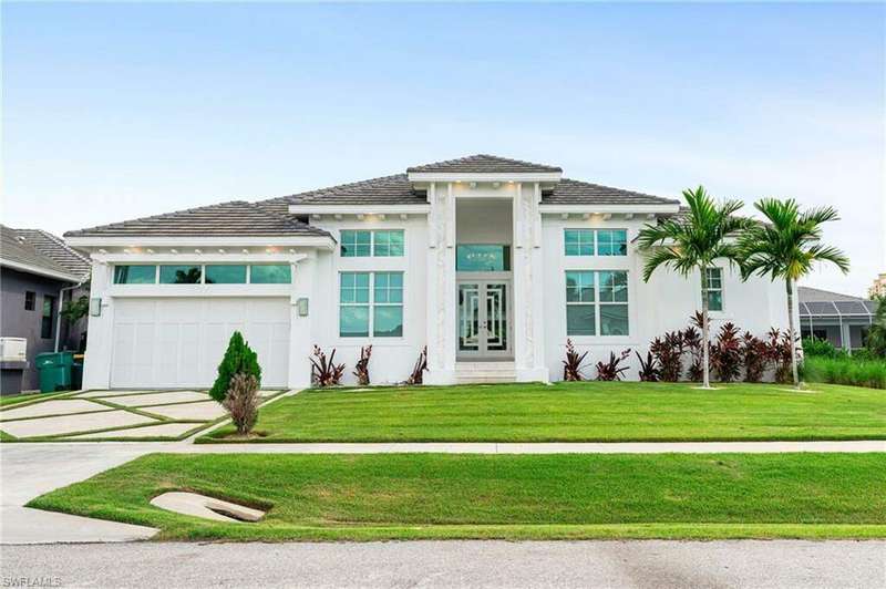 View of front of property featuring a garage and a front lawn