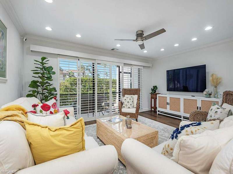 Living room with crown molding, ceiling fan, and wood-type flooring