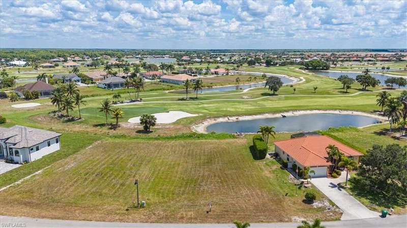 Aerial perspective of suburban area featuring a golf course and a nearby body of water