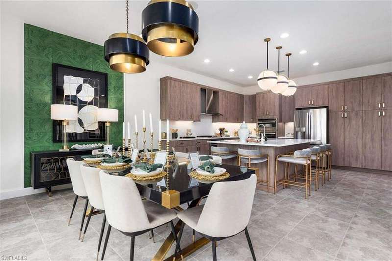Kitchen featuring wall chimney exhaust hood, dark brown cabinetry, sink, decorative light fixtures, and an island with sink