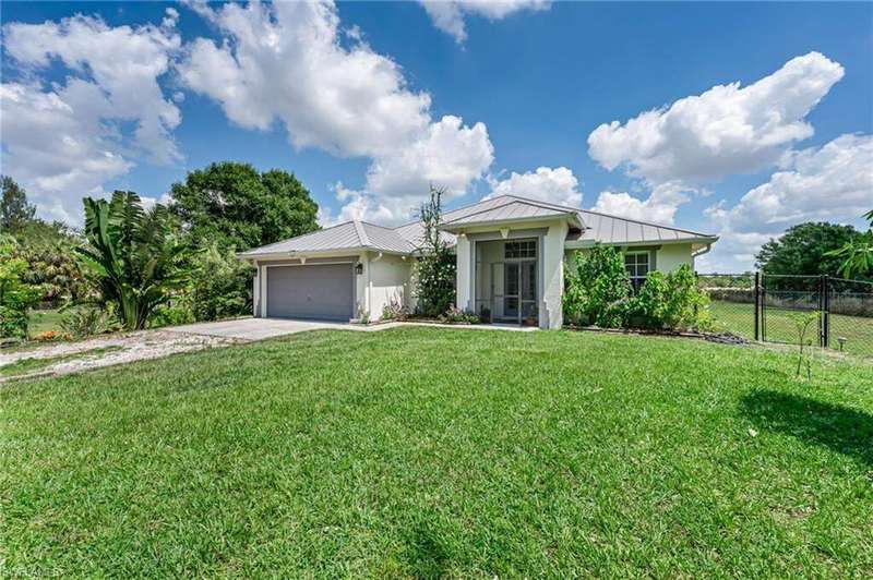 Single story home with a standing seam roof, stucco siding, driveway, an attached garage, and metal roof