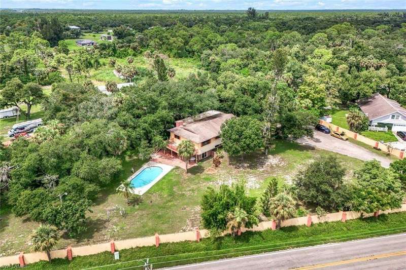 Back of house with a poolside deck, a large yard with a brick paved patio