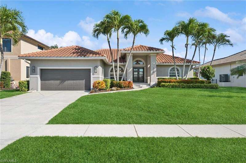 Mediterranean / spanish-style house featuring a garage, a tile roof, stucco siding, a front lawn, and driveway