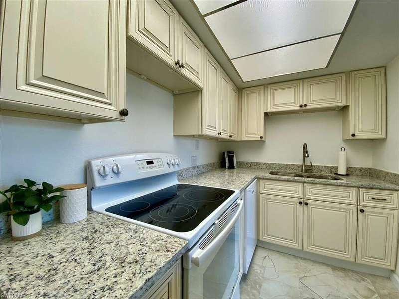 Kitchen featuring white appliances, light marble finish floors, and cream cabinets