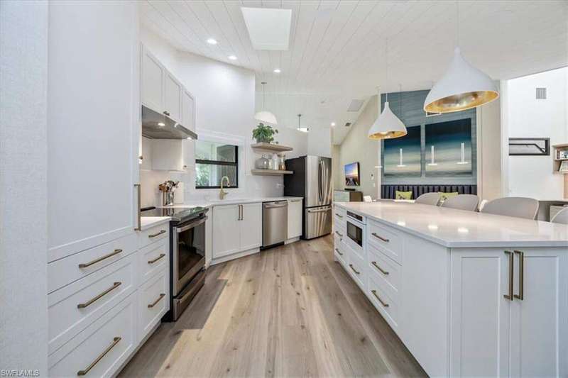 Kitchen with white cabinetry, open shelves, a kitchen bar, appliances with stainless steel finishes, and recessed lighting