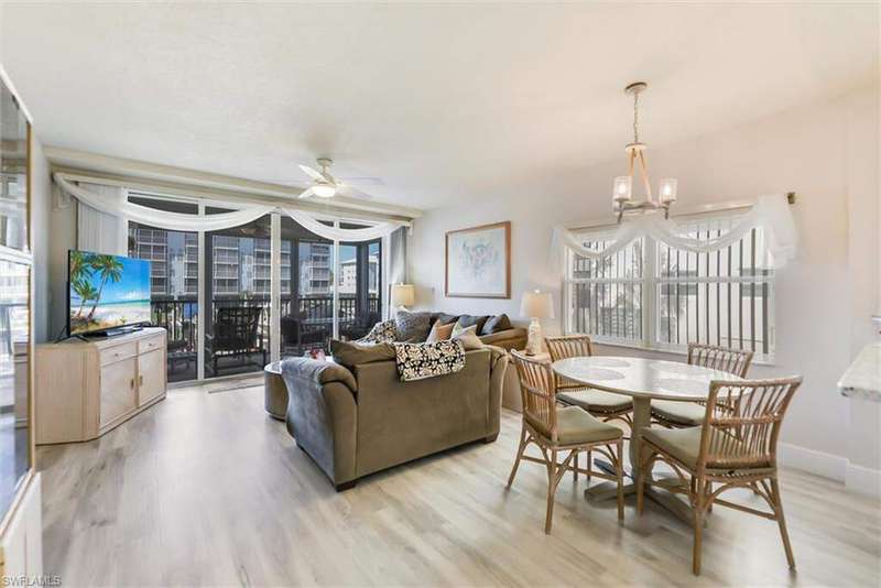 Living area featuring ceiling fan, light wood-type flooring, and a chandelier