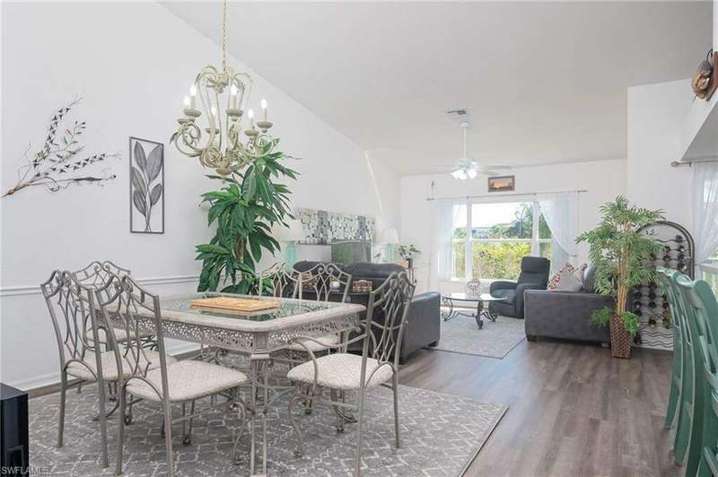 Dining room featuring dark wood-type flooring, vaulted ceiling, and ceiling fan with notable chandelier