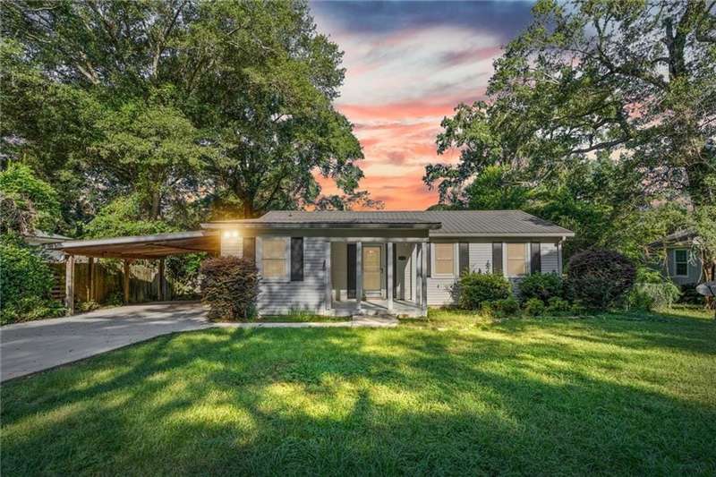 Single story home with a lawn, concrete driveway, an attached carport, and a metal roof