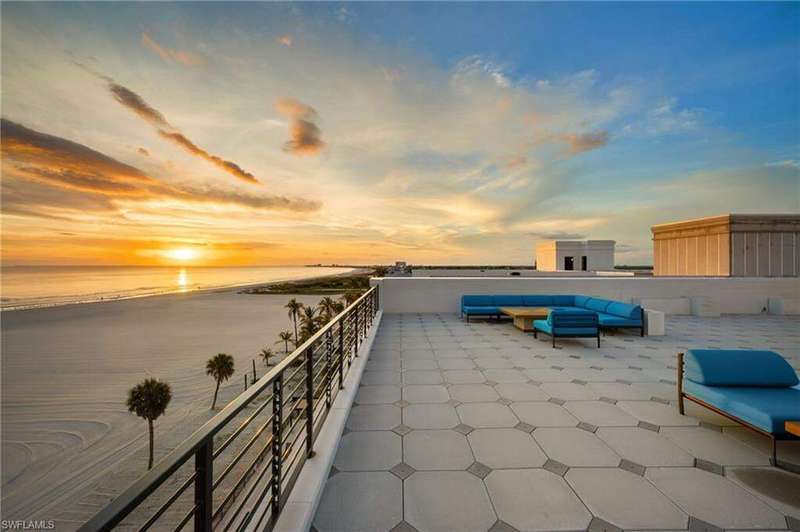Patio terrace at dusk featuring a patio area, view of water and beach, and an outdoor living space