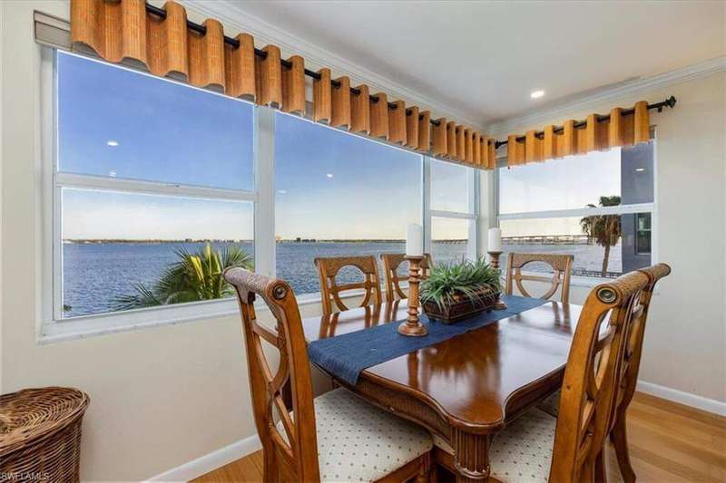 Dining space featuring wood finished floors, a water view, and crown molding