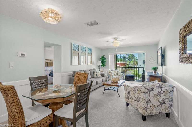 Carpeted dining space featuring a wainscoted wall, a ceiling fan, and a decorative wall