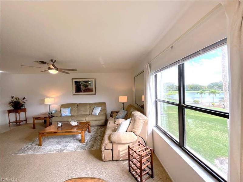 Living room with carpet flooring, a ceiling fan, and visible vents