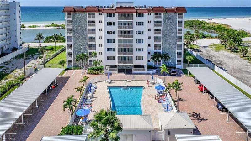 Community pool featuring view of water and beach