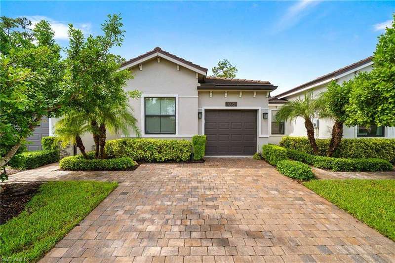 View of front of property with decorative driveway, a garage, stucco siding, and a tiled roof