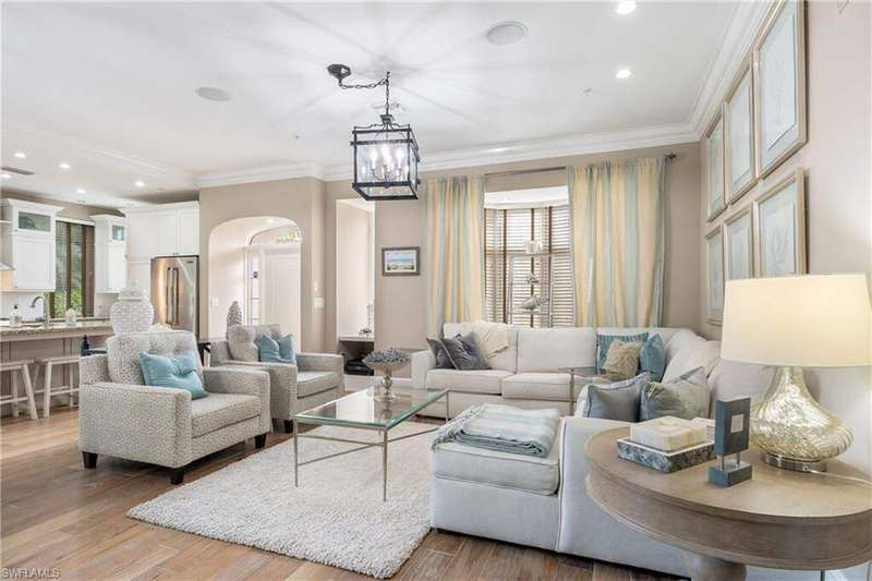 Living room with light wood finished floors, arched walkways, recessed lighting, and ornamental molding