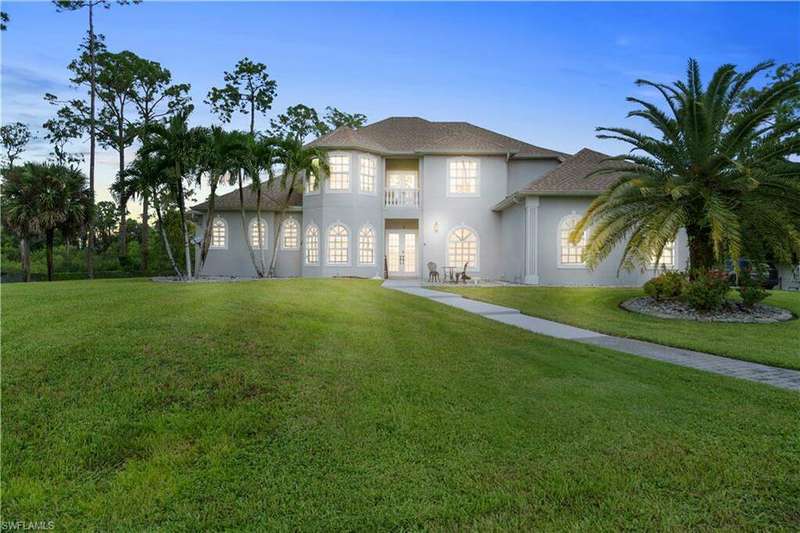 View of front of home featuring french doors, a balcony, and a yard