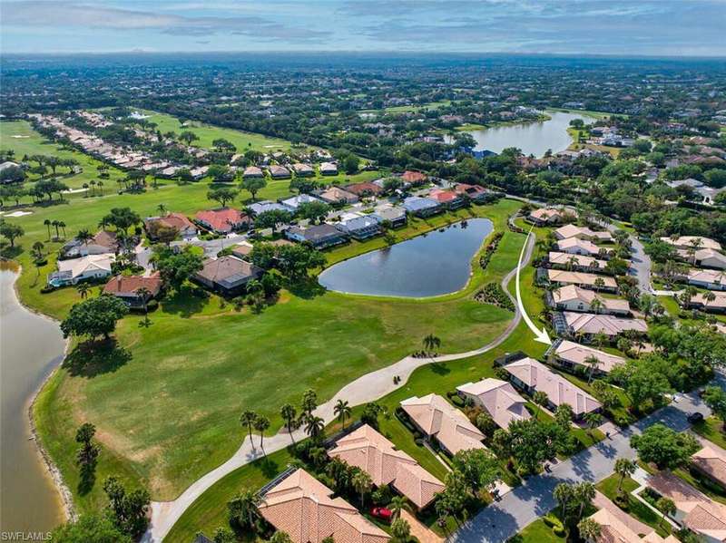 Aerial view of residential area featuring a nearby body of water and a golf course