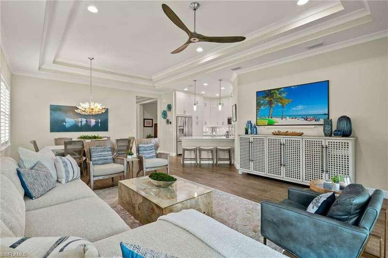 Living room featuring hardwood / wood-style floors, ceiling fan with notable chandelier, a raised ceiling, and crown molding