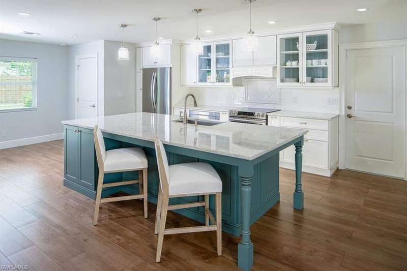 Kitchen featuring appliances with stainless steel finishes, white cabinets, a breakfast bar area, decorative backsplash, and recessed lighting