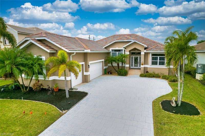 View of front facade featuring a front yard, stucco siding, decorative driveway, and a tile roof