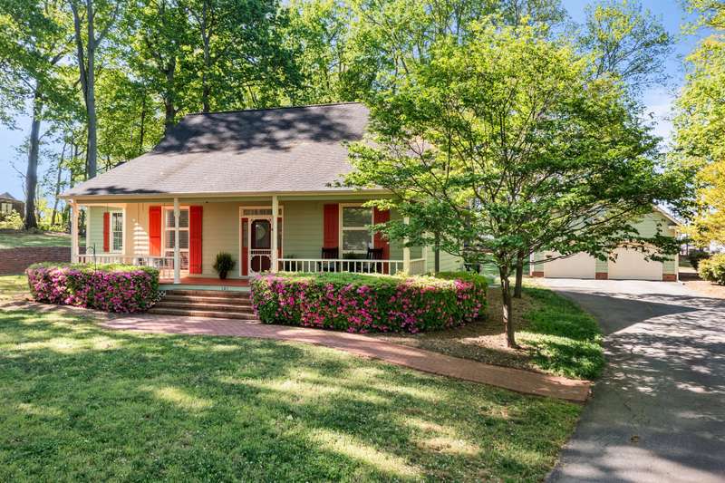 Beautiful Cape Cod-style home with covered rocking chair front porch, vibrant shutters, and mature landscaping.
