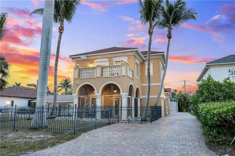 Front view of the house and long driveway during sunset.