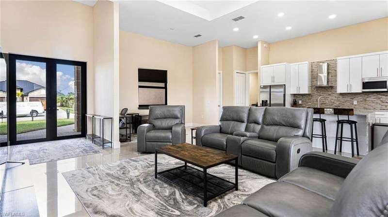 Living area with recessed lighting, visible vents, and a towering ceiling