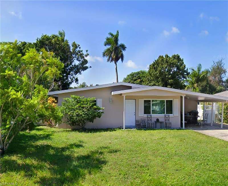 View of front of home featuring a front lawn, a carport, stucco siding, and driveway