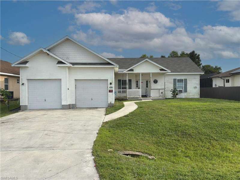 Ranch-style home featuring a porch, driveway, and a garage
