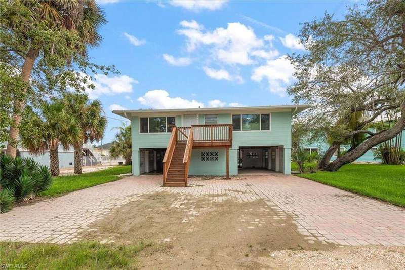 Coastal inspired home with a patio area, stairs, a carport, decorative driveway, and a front lawn