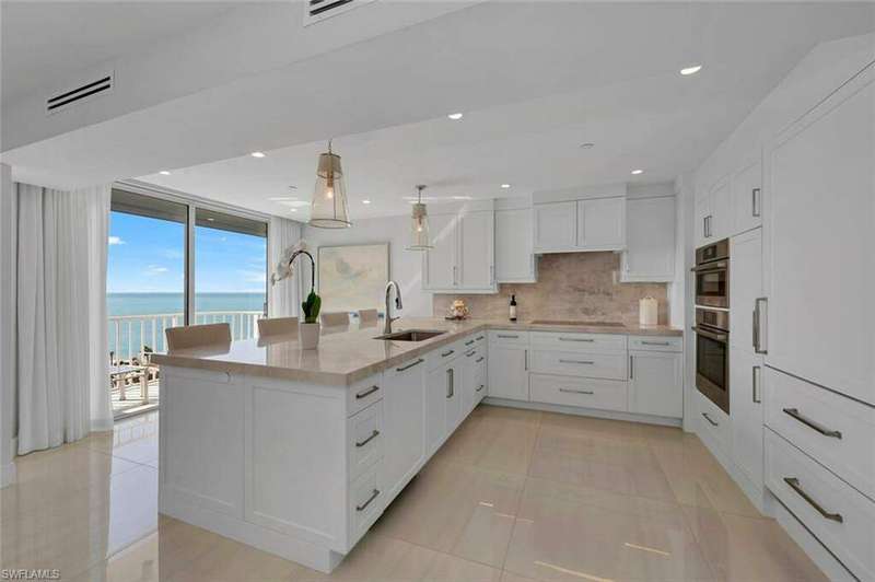 Kitchen featuring decorative backsplash, white cabinets, a sink, a wall of windows, and a peninsula