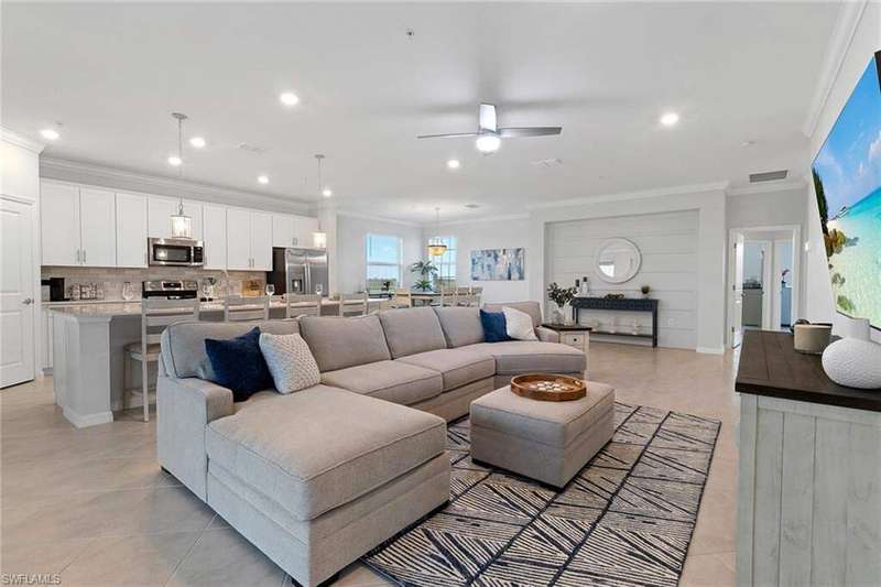 Tiled living room featuring ceiling fan and crown molding