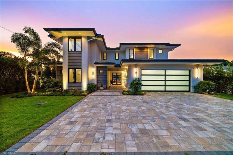 View of front of house with decorative driveway, a front yard, french doors, stucco siding, and an attached garage