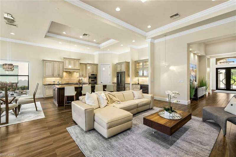 Living room featuring dark wood-type flooring, crown molding, wine cooler, and a tray ceiling