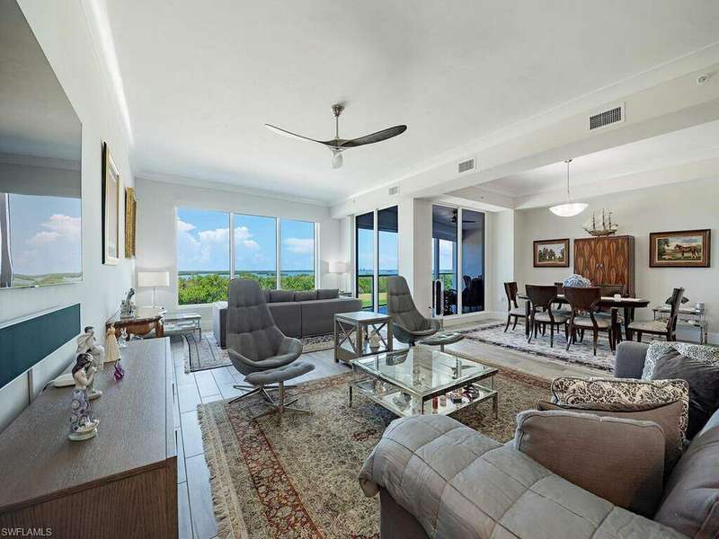 Tiled living room featuring ceiling fan and ornamental molding