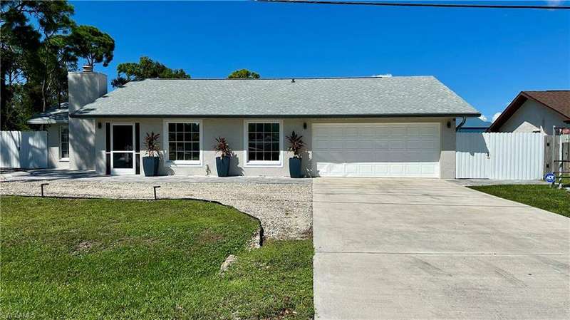 Ranch-style house featuring a garage and a front lawn