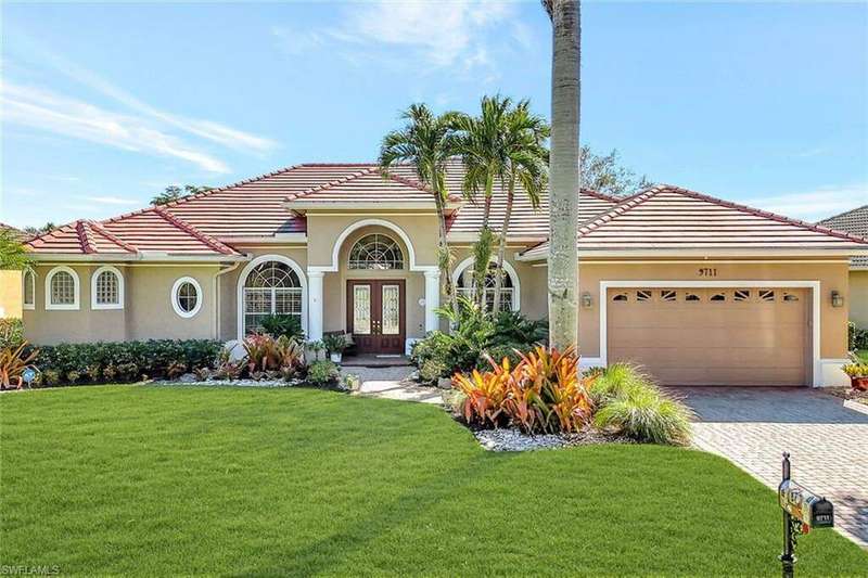 This single-story house has a manicured yard, a two-car deep garage, and double entry doors.